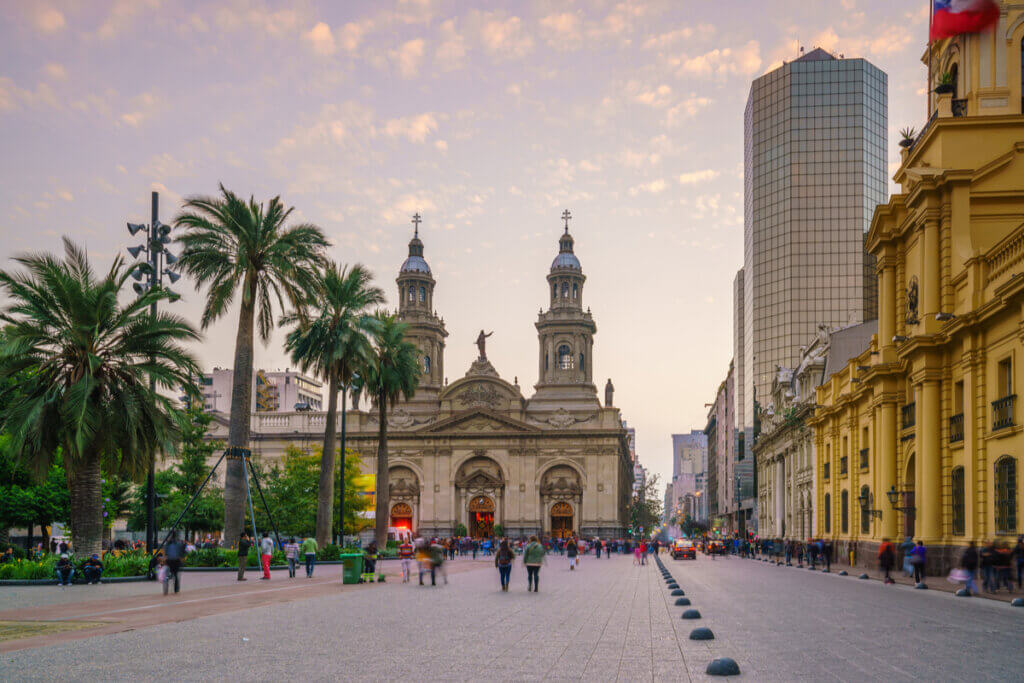 Vista da Plaza de Armas, em Santiago, com uma igreja e pessoas caminhando 