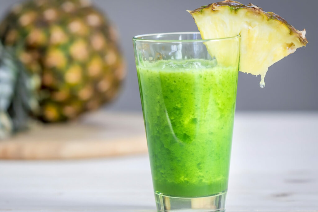 Suco verde em um copo transparente decorado com abacaxi