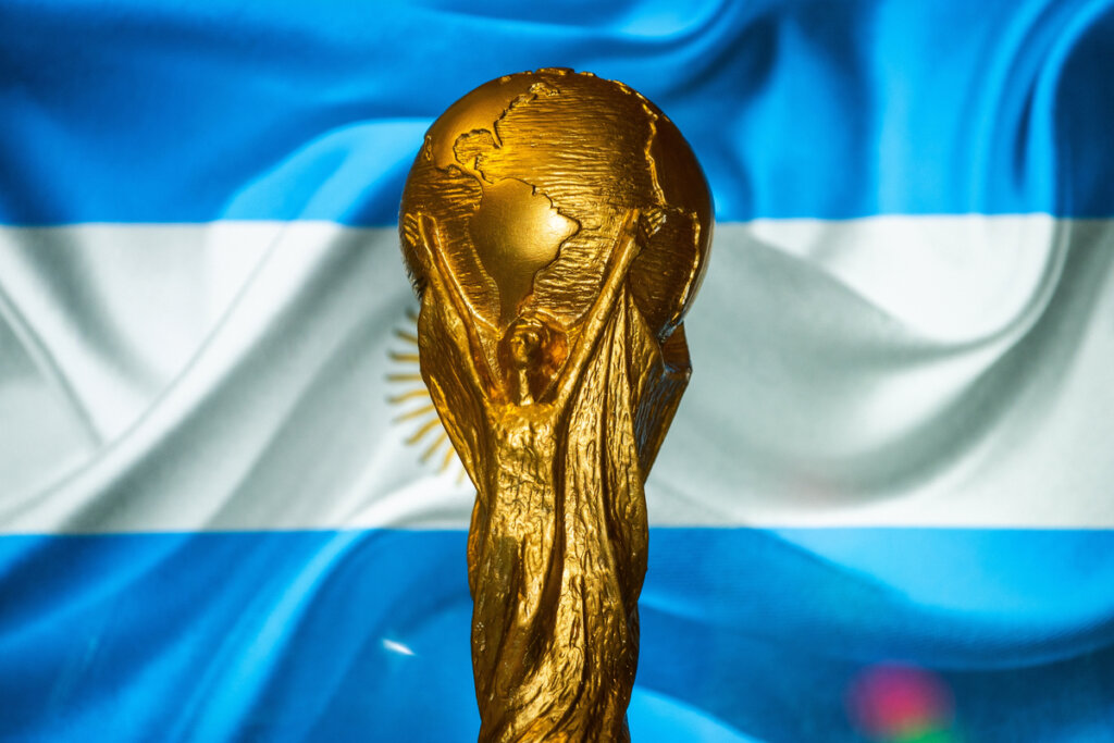 Taça da copa do mundo com a bandeira da Argentina ao fundo 