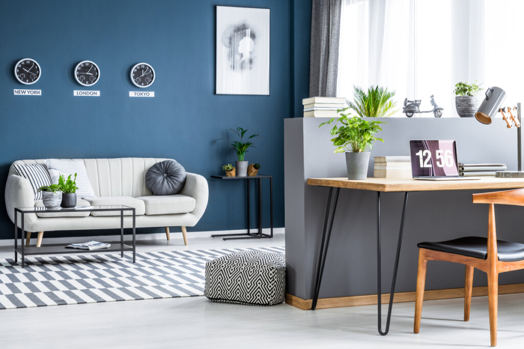 Vista sala de estar com sofá cinza, banco, parede azul e objetos decorativos