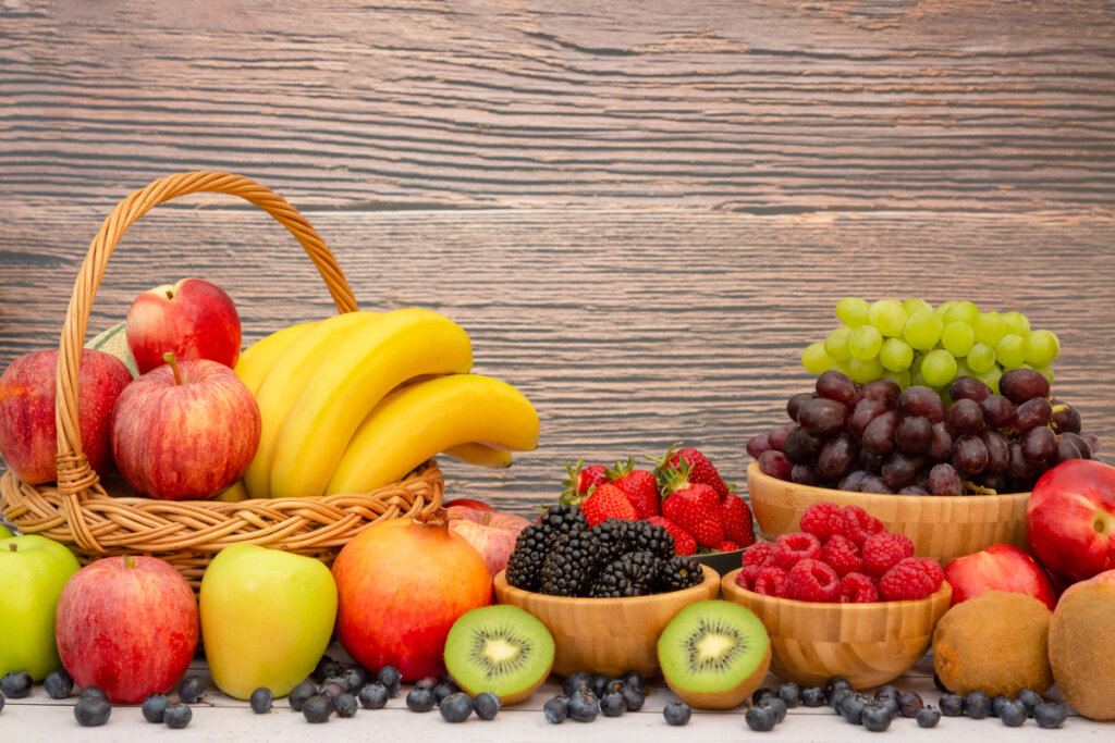 Cesta e bowls com diversas frutas (banana, kiwi, maçã, framboesa, uvas)
