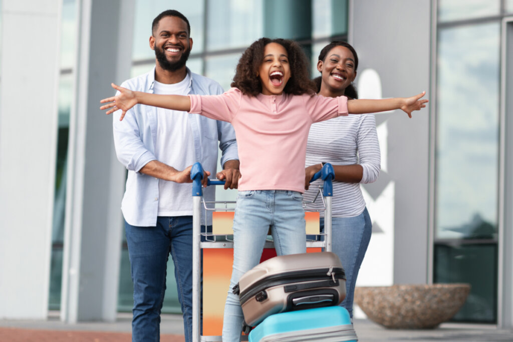 Família feliz em um aeroporto com carinho de mala