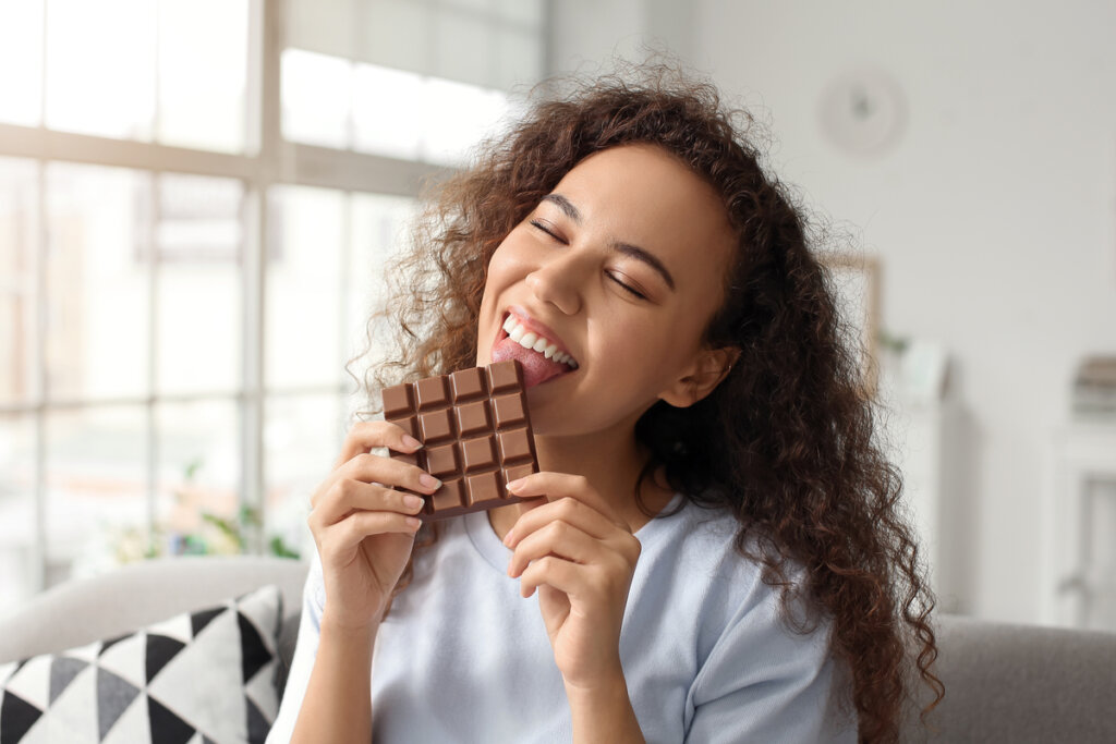 Mulher sorrindo segurando barra de chocolate