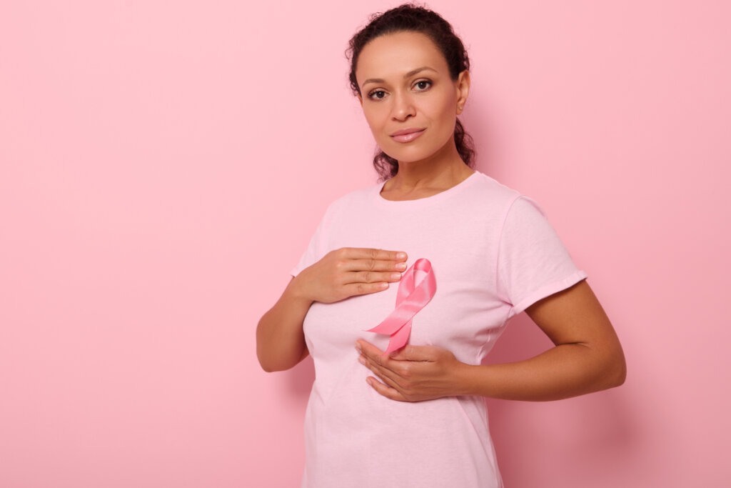 Mulher com laço rosa da luta contra o câncer de mama no seio em fundo rosa-claro