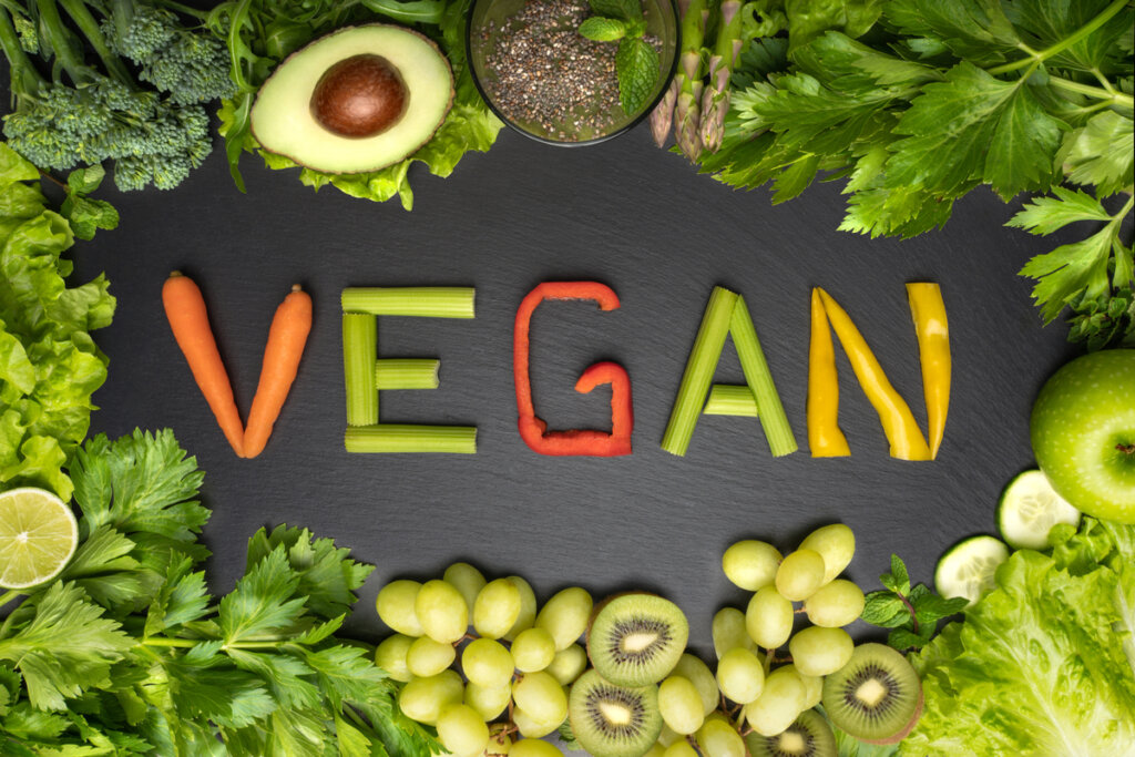 Vegan escrito com alimentos e outros alimentos verdes ao redor