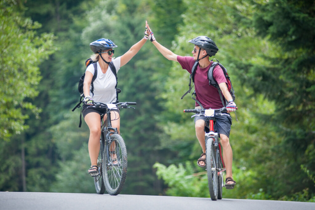 Duas pessoas comemorando enquanto andam de bicicleta