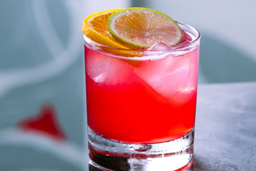 Bebida vermelha em um copo de vidro com rodelas de laranja e limão