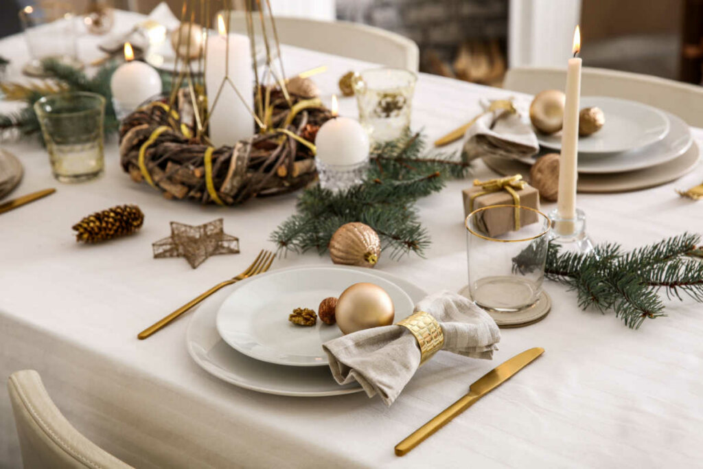Mesa com toalha branca, prato branco e talheres dourados