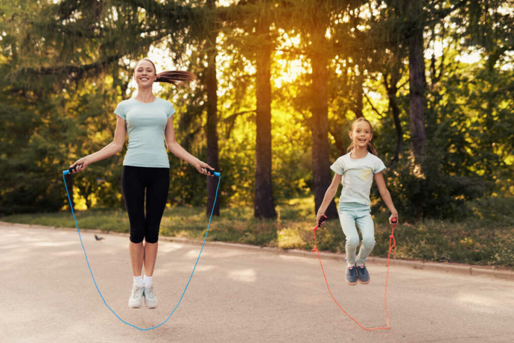 Mulher e criança pulando corda no parque ao ar livre