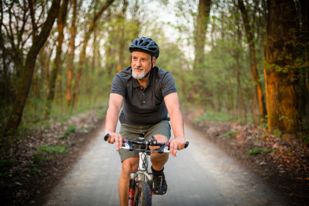 Homem mais velho andando de bicicleta ao ar livre e usando capacete