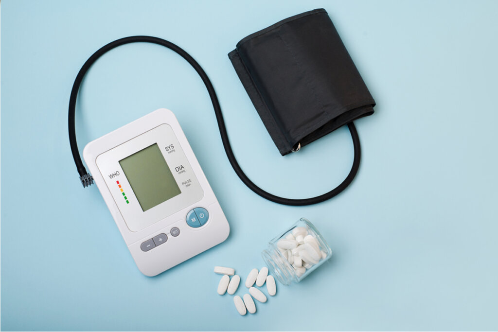 Medidor de pressão arterial e pote caído com comprimidos