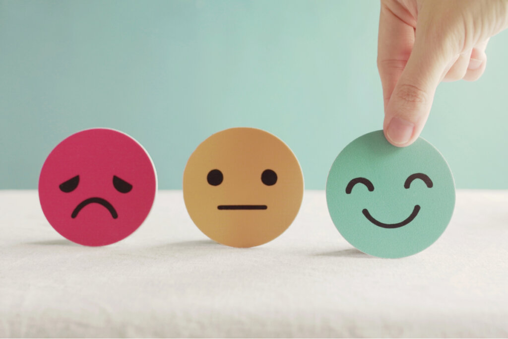 Três emojis e mão escolhendo o emoji feliz