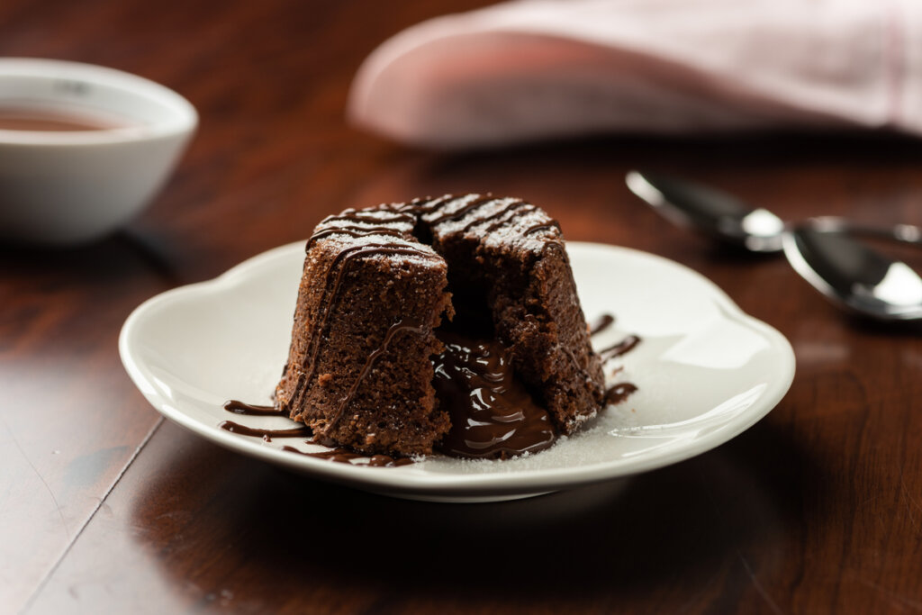 Bolinho de chocolate dentro do prato branco e em cima da mesa de madeira