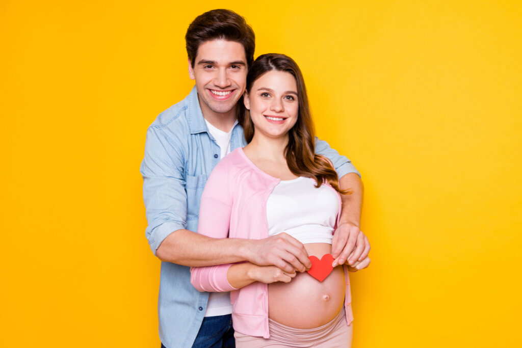 Homem abrançando uma mulher grávida com um coração na barriga