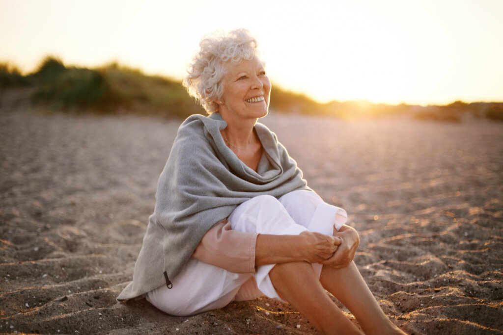 Uma mulher de meia idade sentada na areia de uma praia