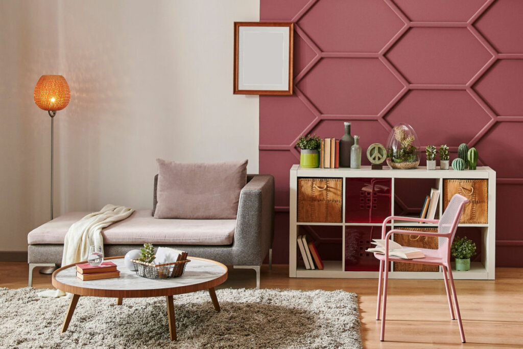 Sala de estar com parede rosa, poltrona, espelho e mesa de centro