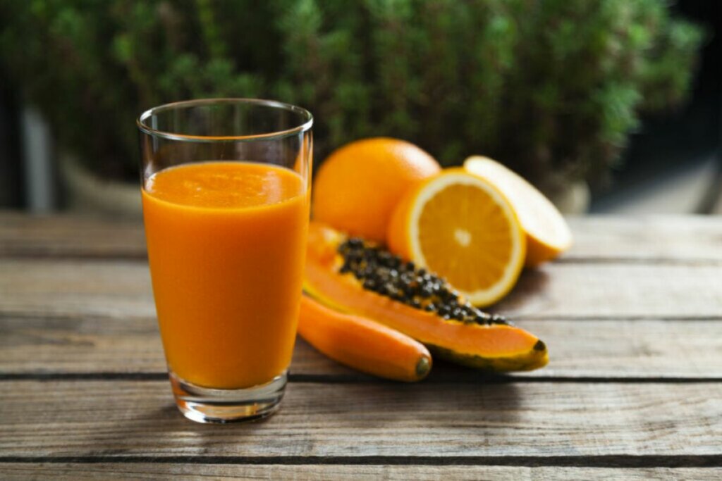 Copo de vidro com suco de laranja e mamão