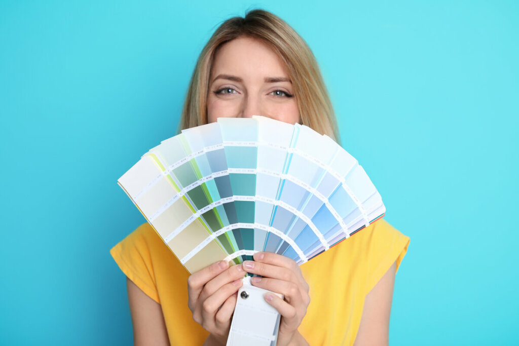 Mulher segurando paleta de cores em frente a um fundo azul