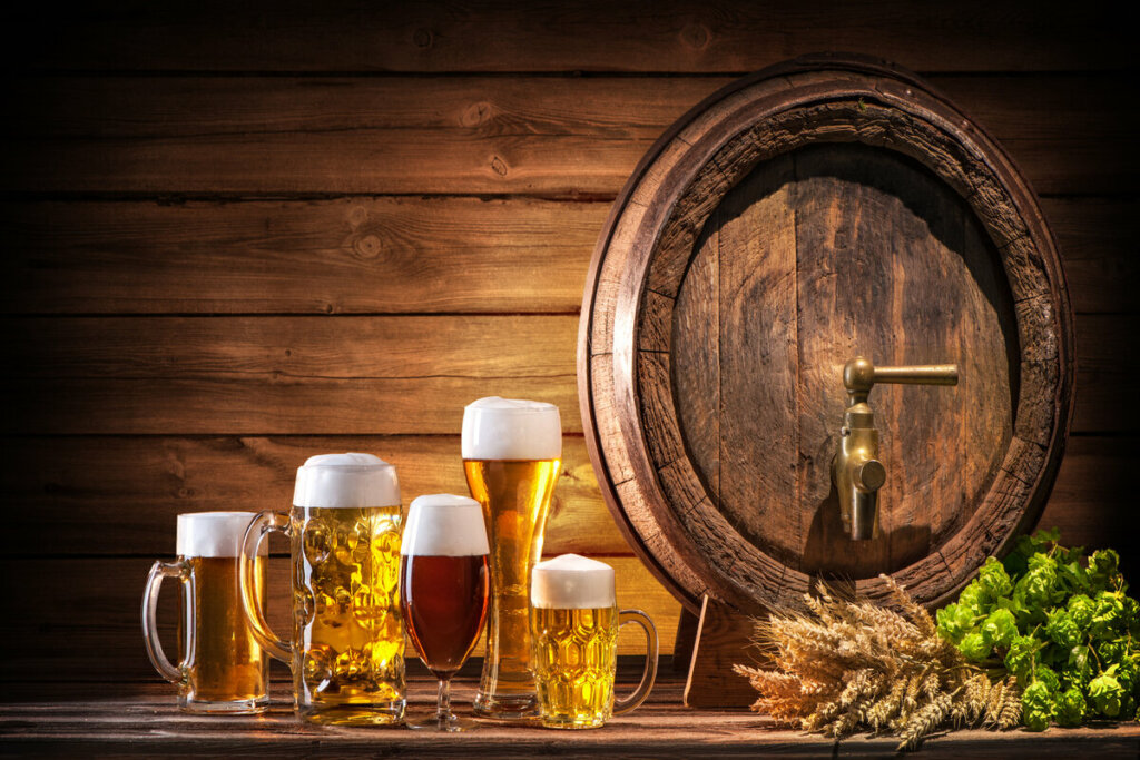 Copos de vidro com cerveja em cima de uma mesa de madeira com barril de fundo