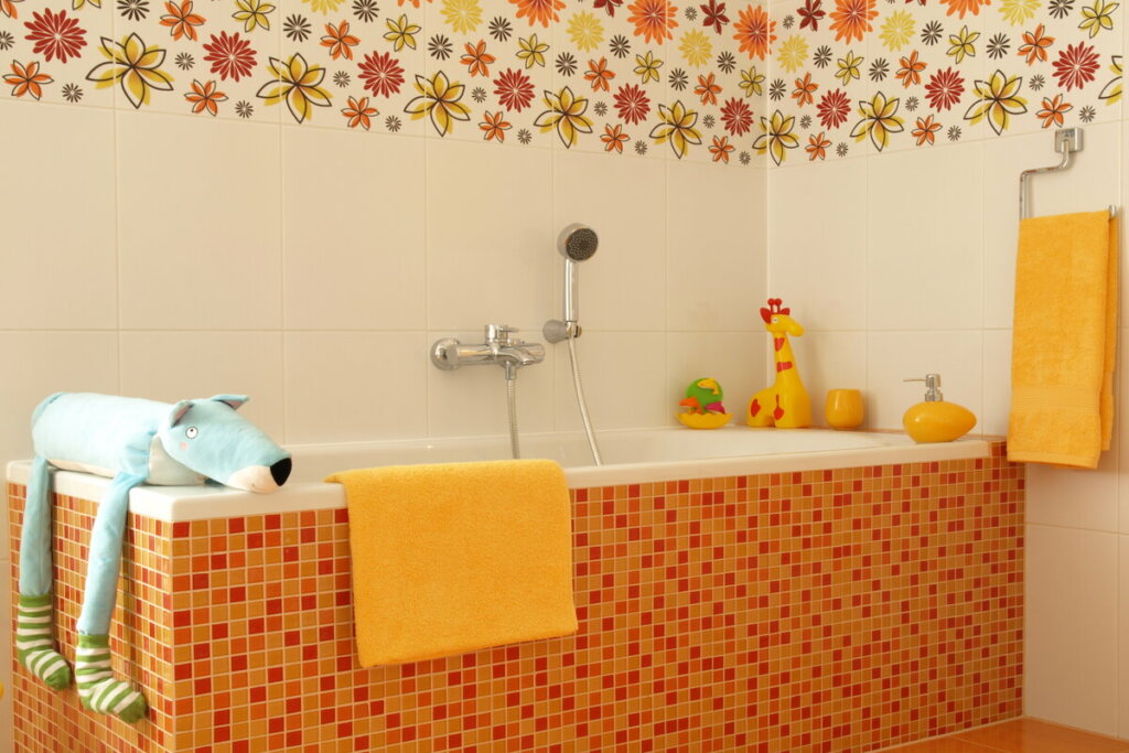 Banheiro com pastilhas laranjas, papel de parede de flores e banheira branca