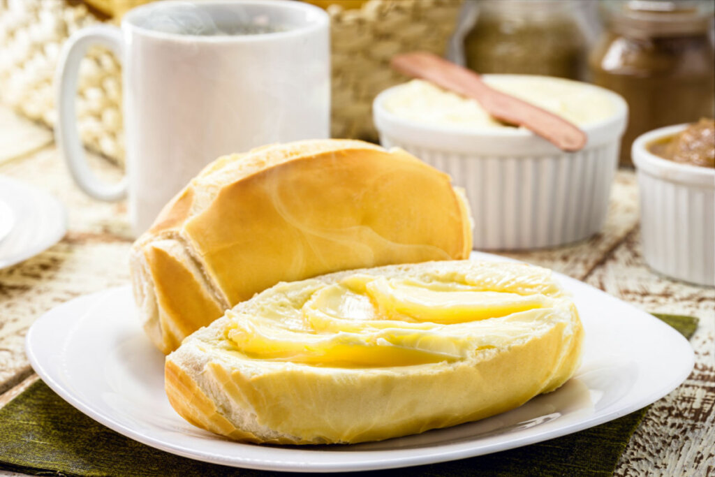 Pão francês com manteiga em prato branco
