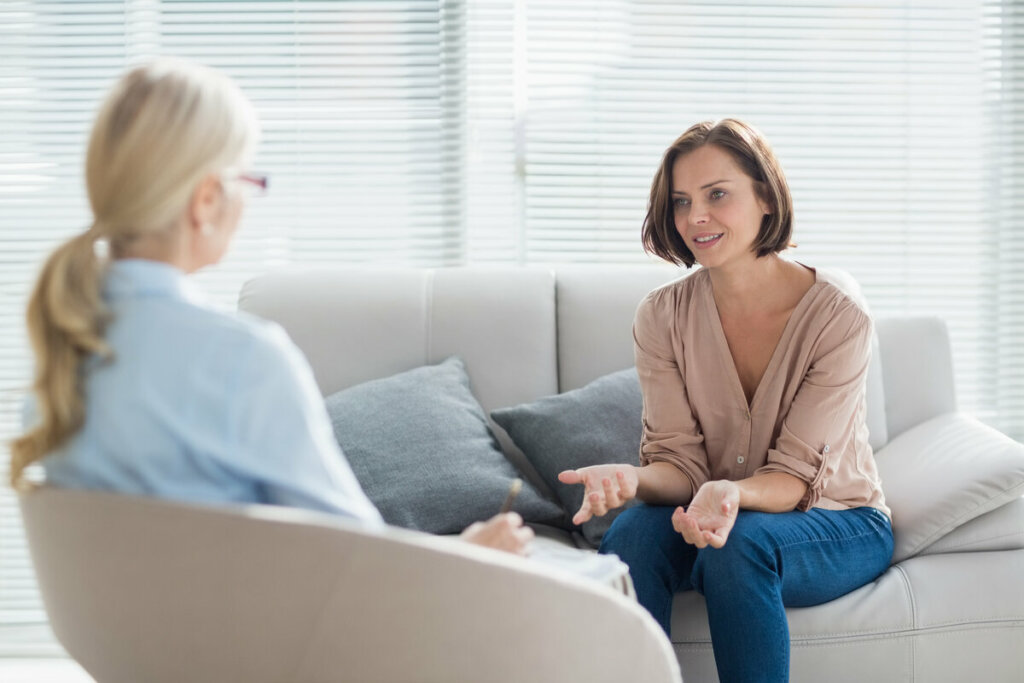 Mulher sentada em um sofá bege conversando com psicóloga