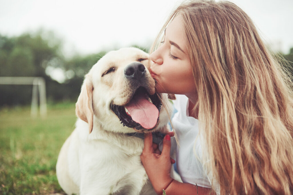 Mulher beijando cachorro sorrindo