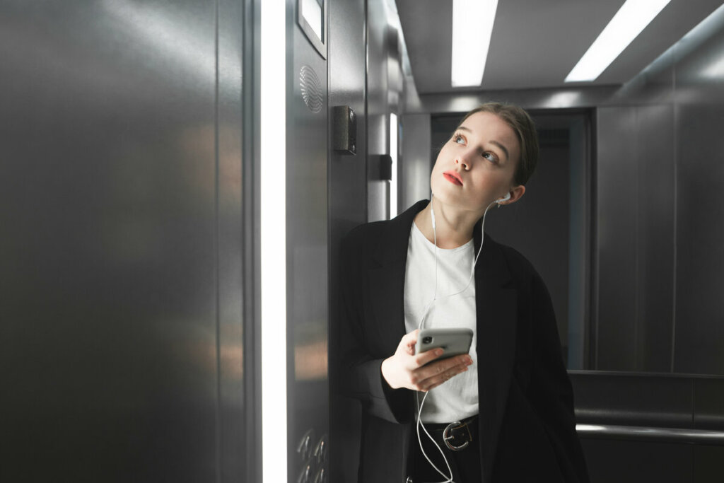 Mulher vestida de preto e branco dentro de um elevador