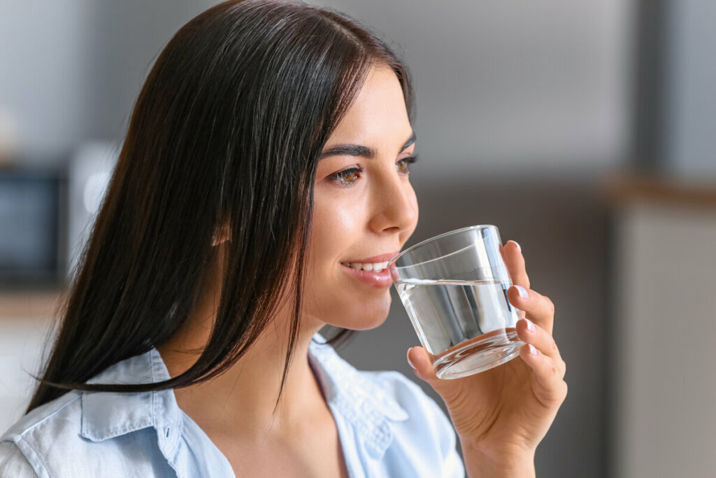 Mulher sorrindo segurando um copo de água