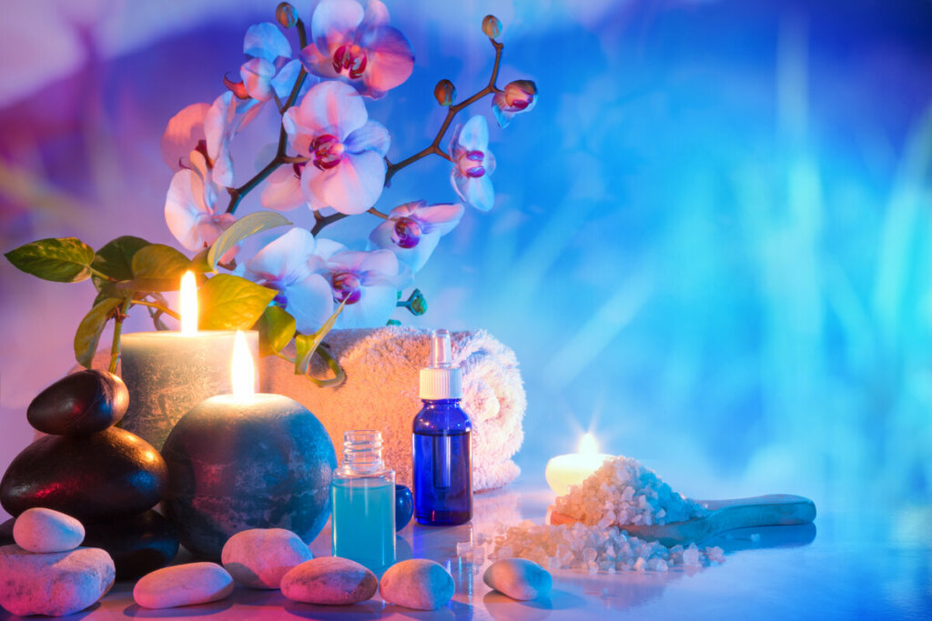 Pedras, velas e orquídea em cima de uma mesa com fundo azul