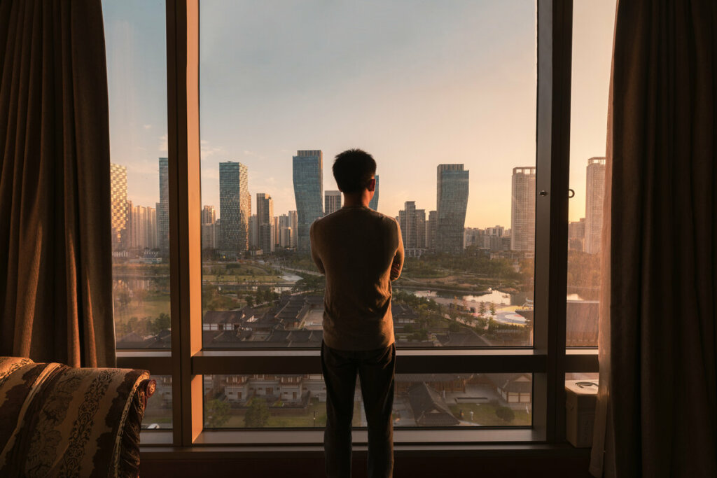 Homem olhando paisagem de uma cidade por uma janela