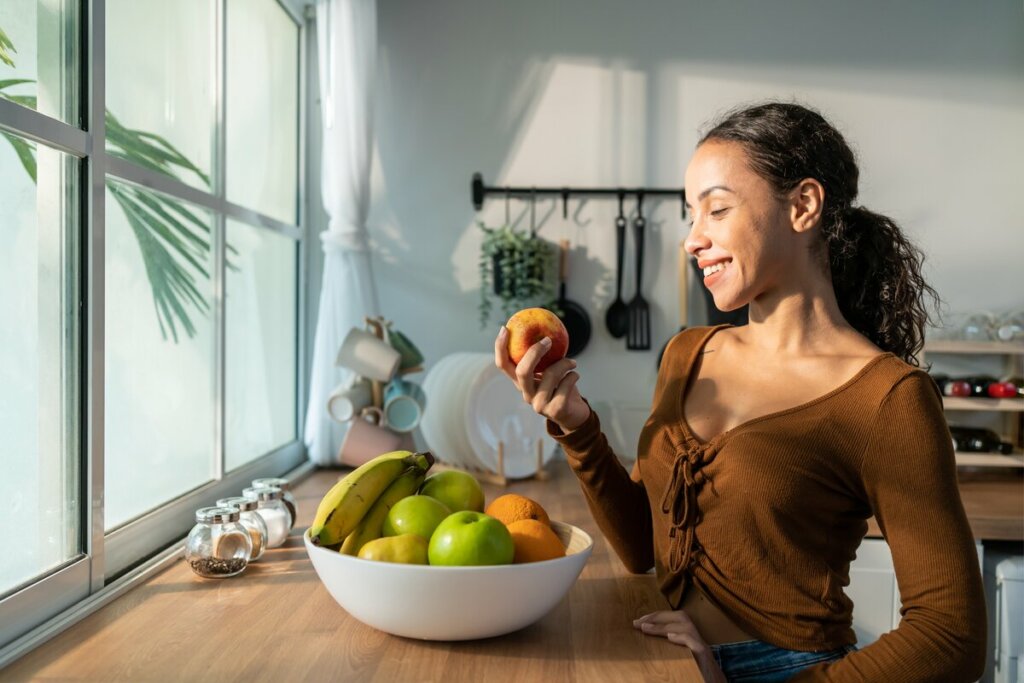 Mulher sorrindo segurando uma maçã na mão