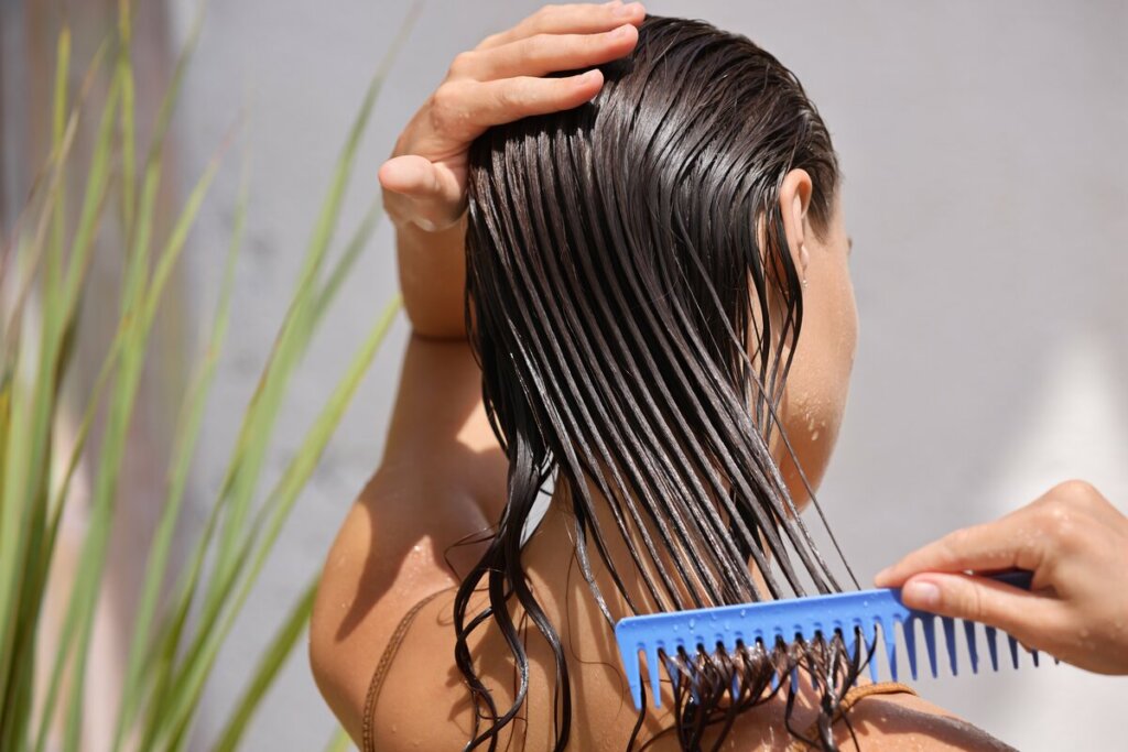 Mulher penteando o cabelo molhado e com creme