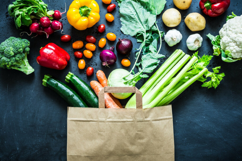 Vegetais e legumes saindo de dentro de uma sacola de papel
