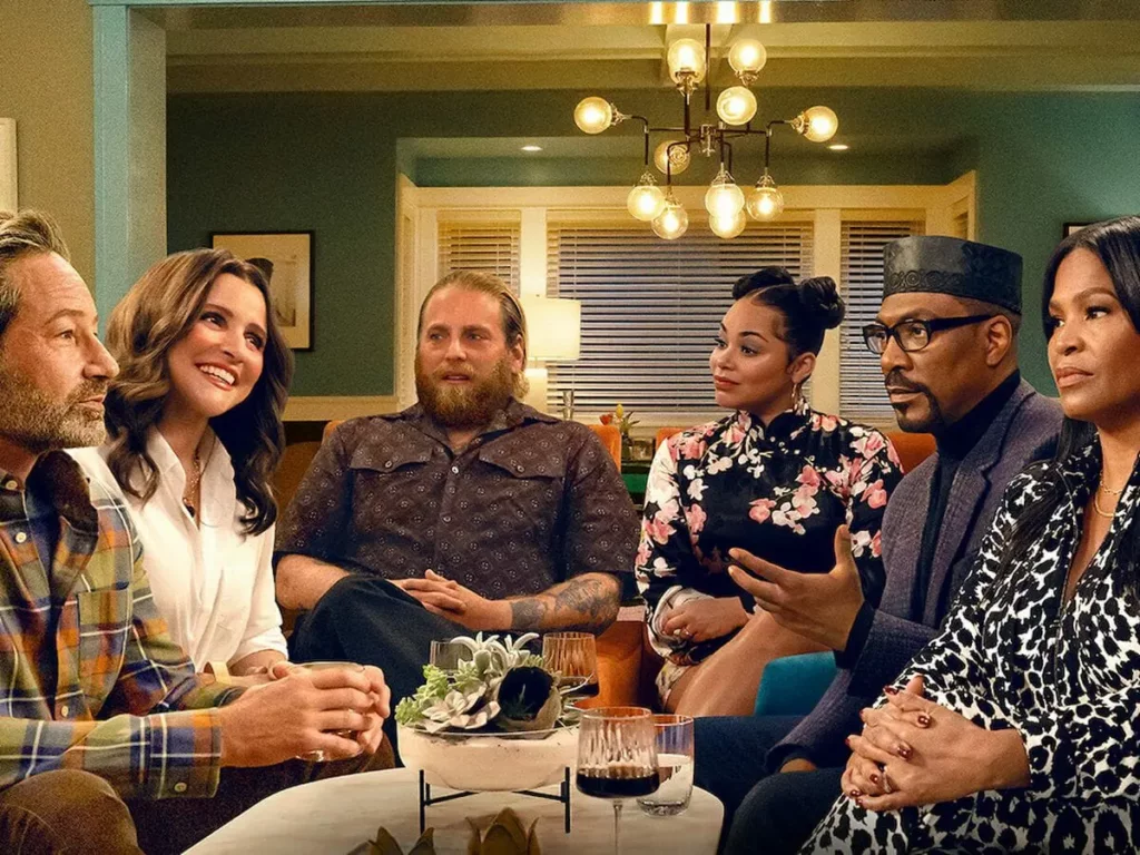 Três pessoas brancas e três pretas conversam em mesa de jantar.