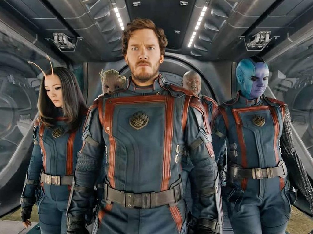 Cinco personagens fictícios do universo galáctico estão em espaçonave, com uniformes de astronauta.
