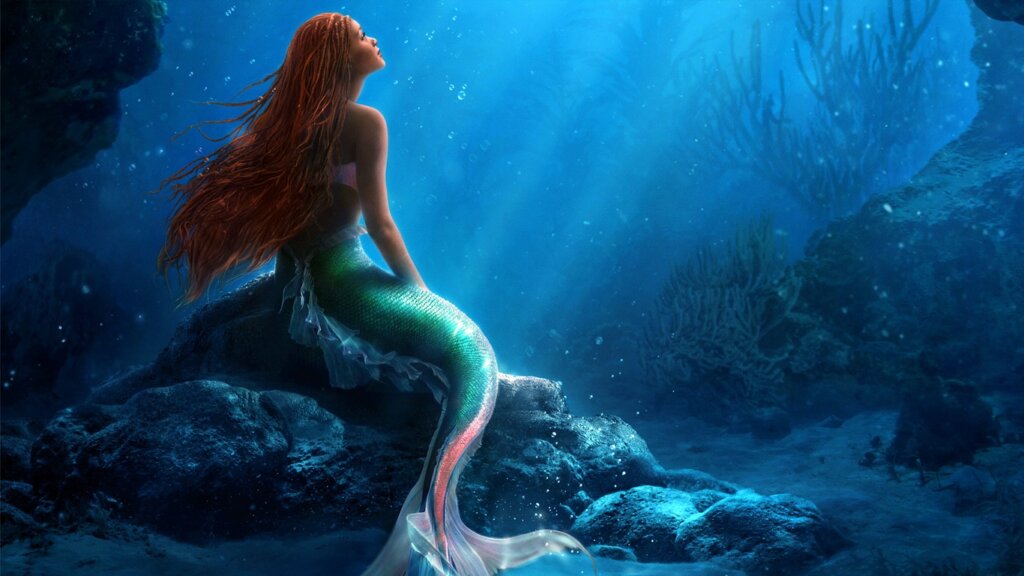 Personagem fictícia de sereia está embaixo do mar olhando para luz solar com expressão pensativa.