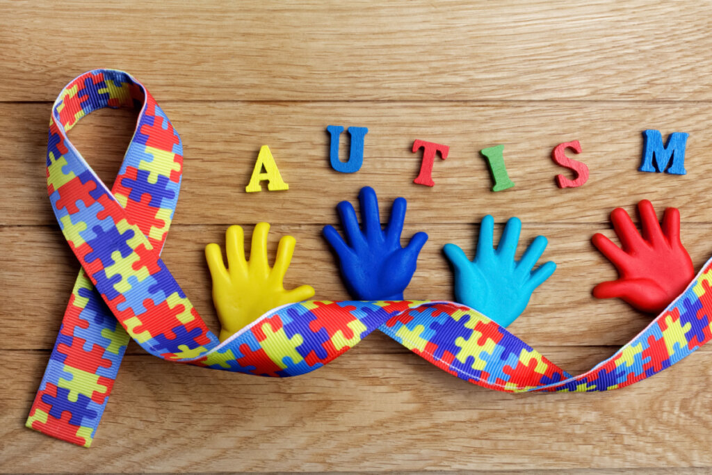 Conceito de consciência do autismo com mãos coloridas no fundo de madeira