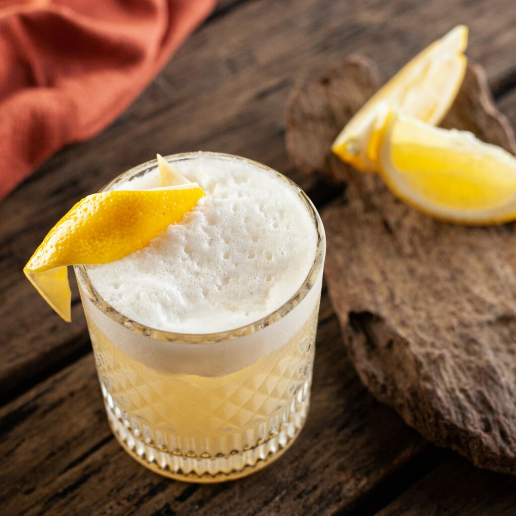 Drink Whisky Sour em copo de vidro com casca de limão