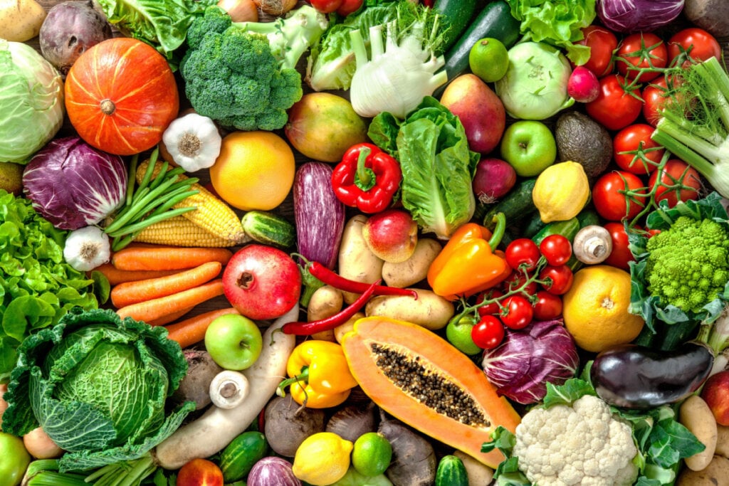 Várias frutas, legumes e verduras misturados, como pimentão, manga, mamão, repolho, berinjela, brócolis, acelga, alho, maçã verde e outros