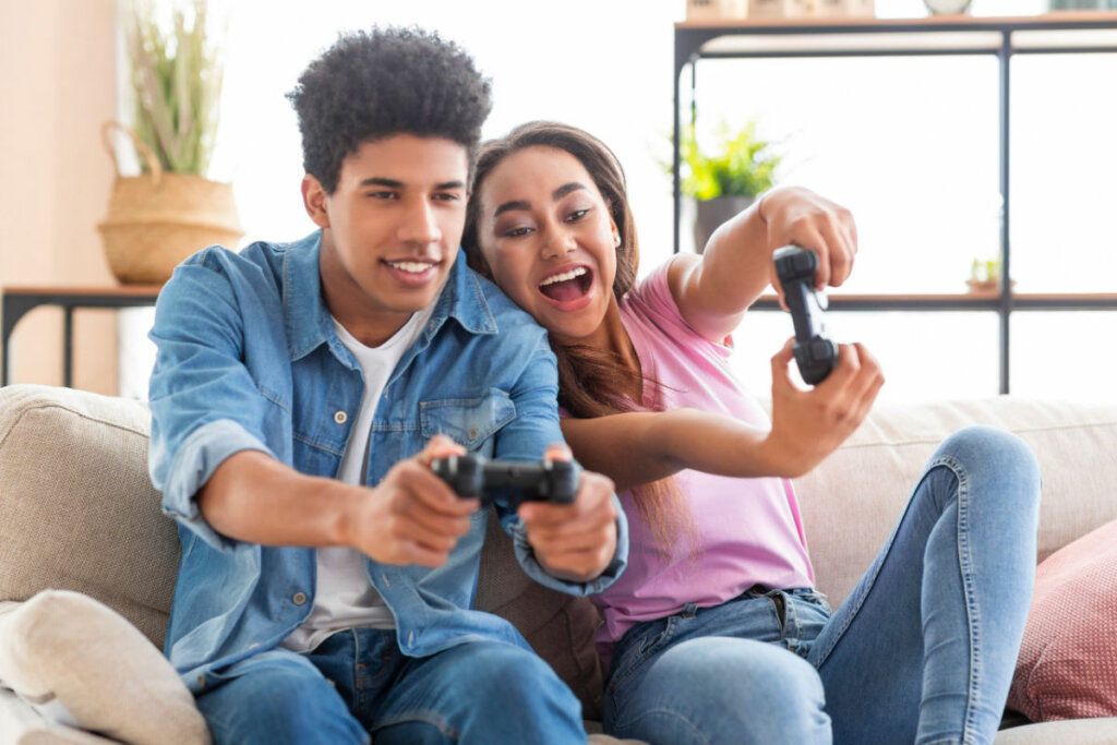 Menino e menina jogando videogame sentados no sofá