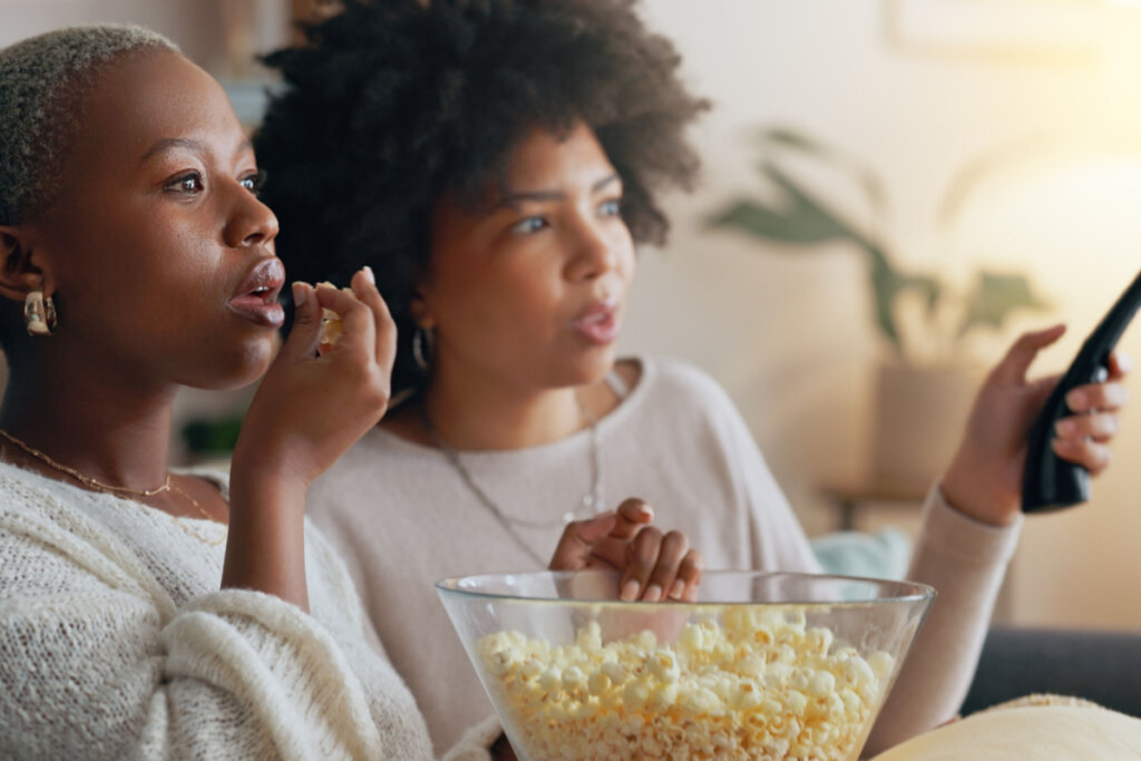 Duas mulheres comendo pipoca e assistindo a um filme