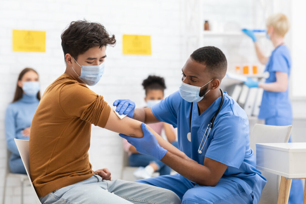 Médico limpando o braço de um homem para aplicar vacina