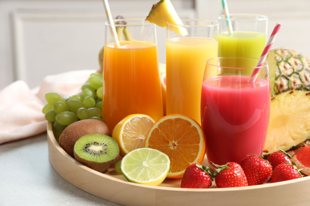 Na foto, quatro tipos de sucos com frutas cortadas