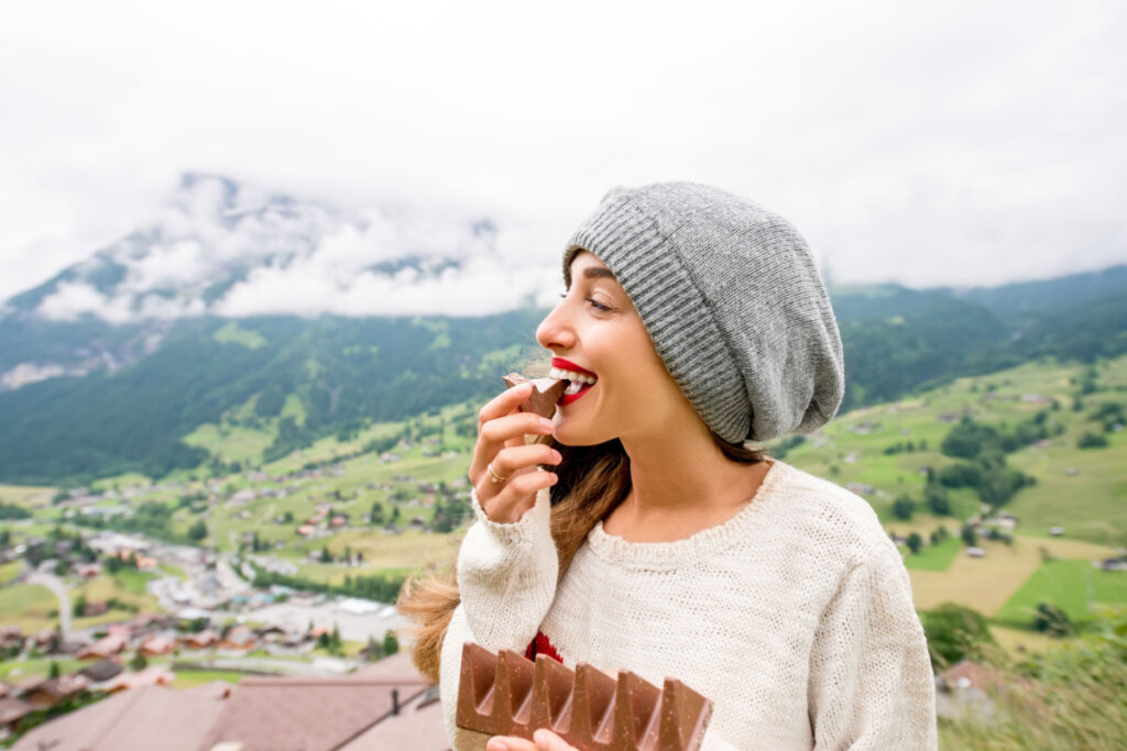 Mulher comendo chocolate em viagem nas montanhas