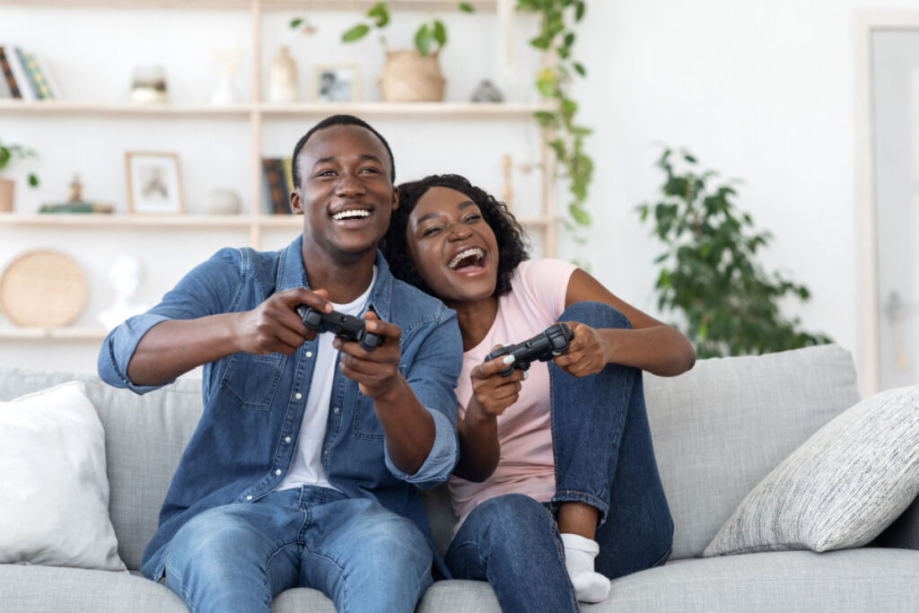 Homem e mulher animados jogando video game juntos em sofá