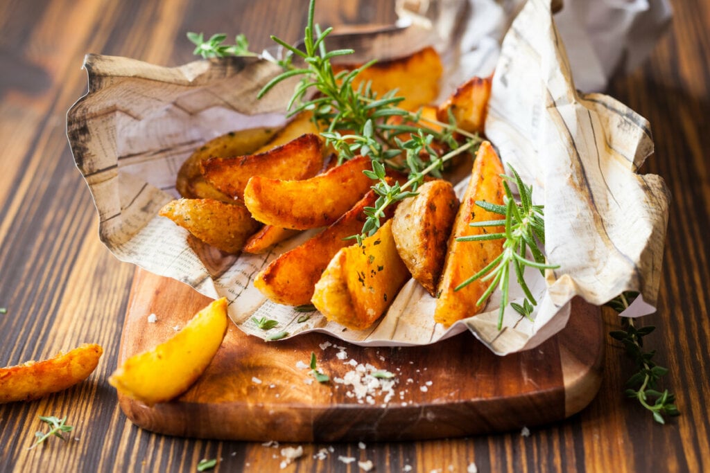 Batatas rústicas em cima de uma tábua de madeira