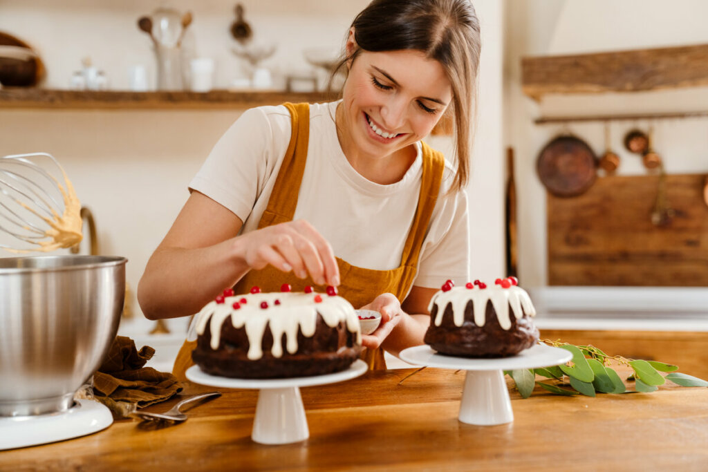 Mulher de avental decorando dois bolos de chocolate