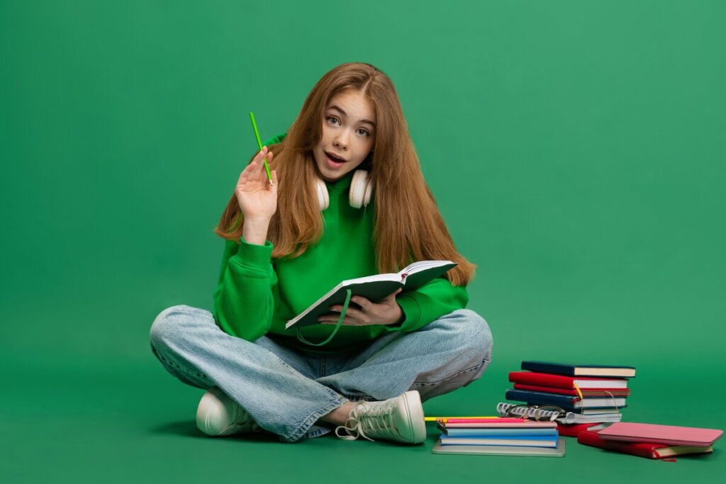 Menina de blusa verde sentada olhando um livro