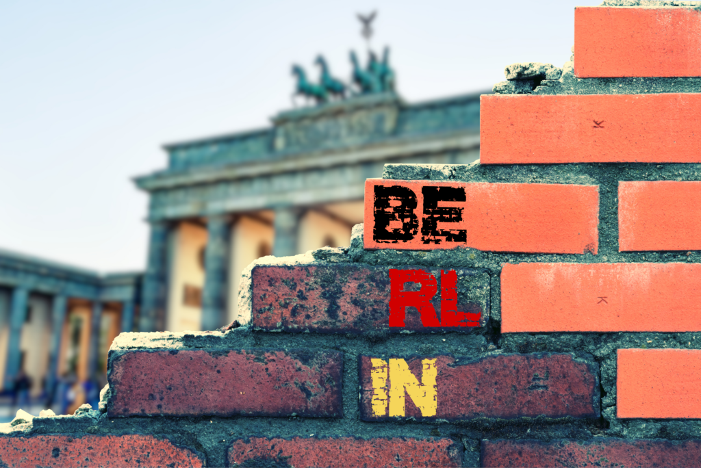 Ilustração de um muro com letras. Está escrito “Berlin”